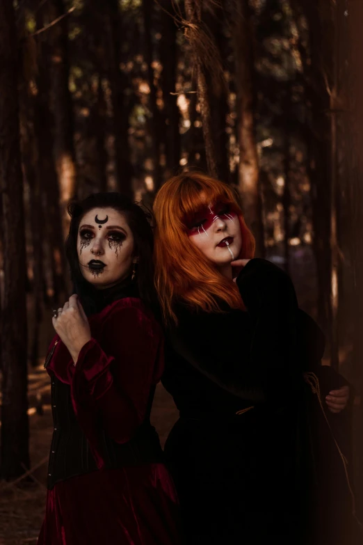 a couple of women standing next to each other in a forest, trending on pexels, gothic art, gothic makeup, wild ginger hair, during a blood moon, black metal face paint