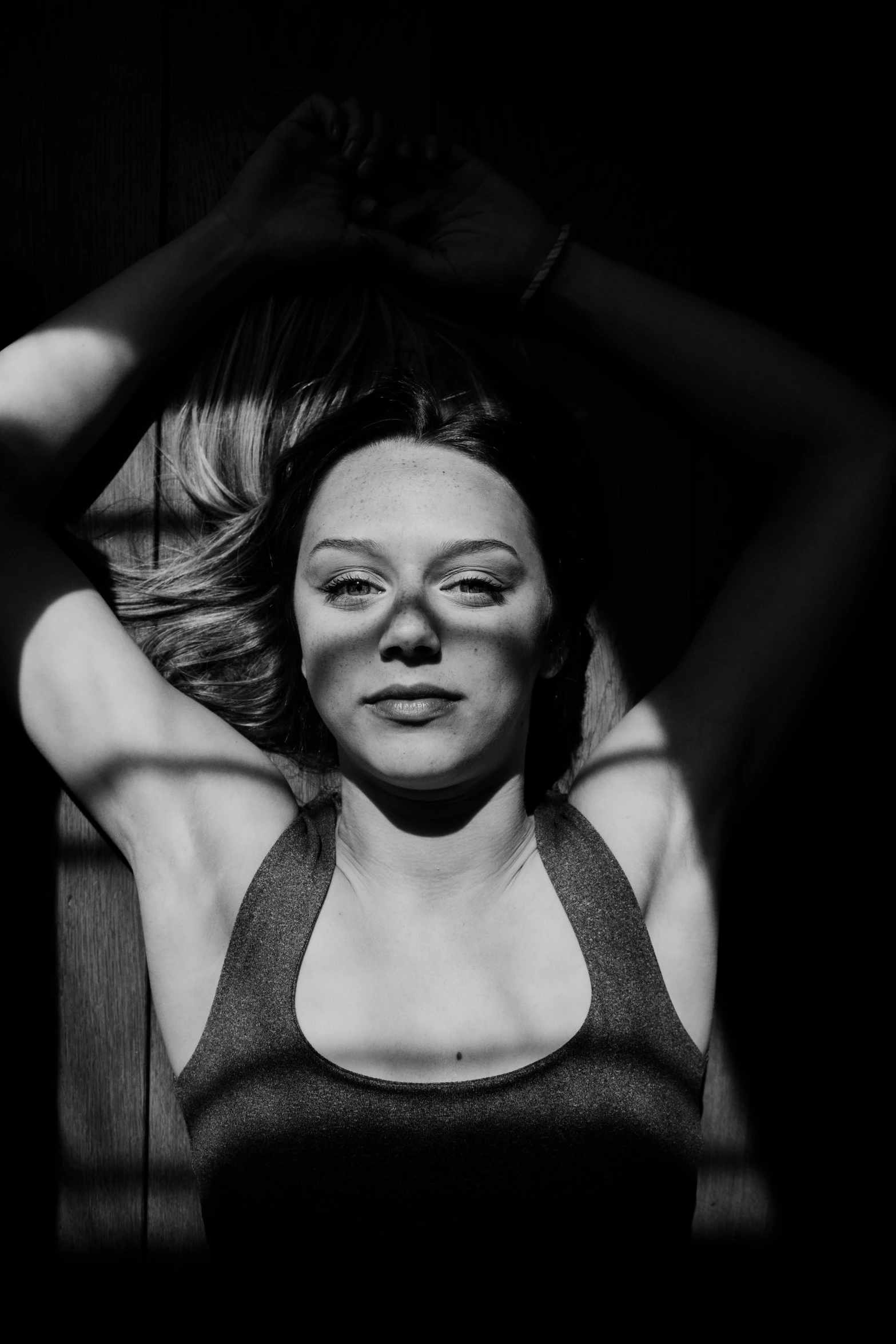 a black and white photo of a woman with her hands on her head, a black and white photo, inspired by Peter Basch, pexels contest winner, clarice starling, she is laying on her back, sydney sweeney, sun glare