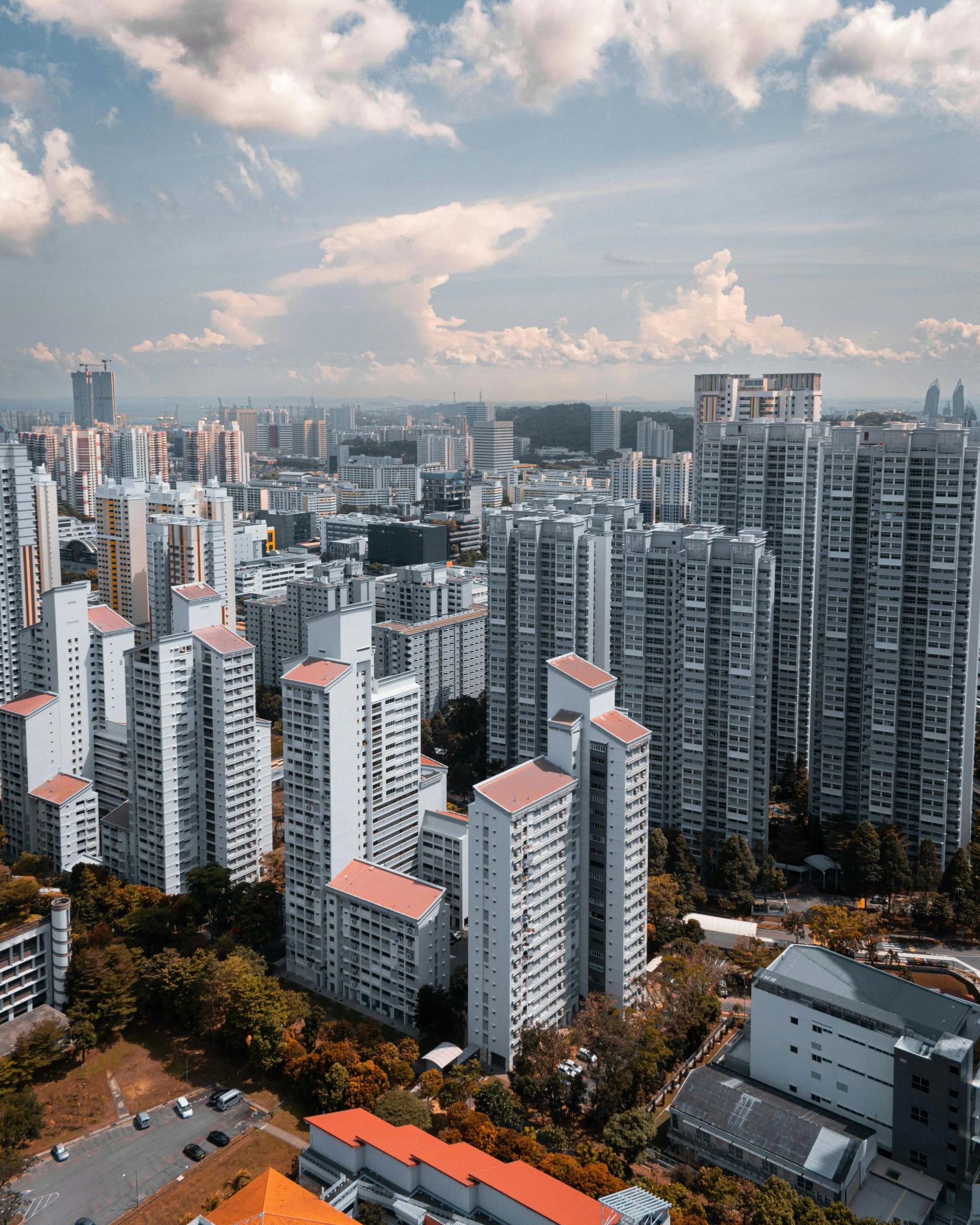 an aerial view of a city with tall buildings, inspired by Cheng Jiasui, pexels contest winner, happening, concrete housing, set on singaporean aesthetic, city on a hillside, skyline showing from the windows