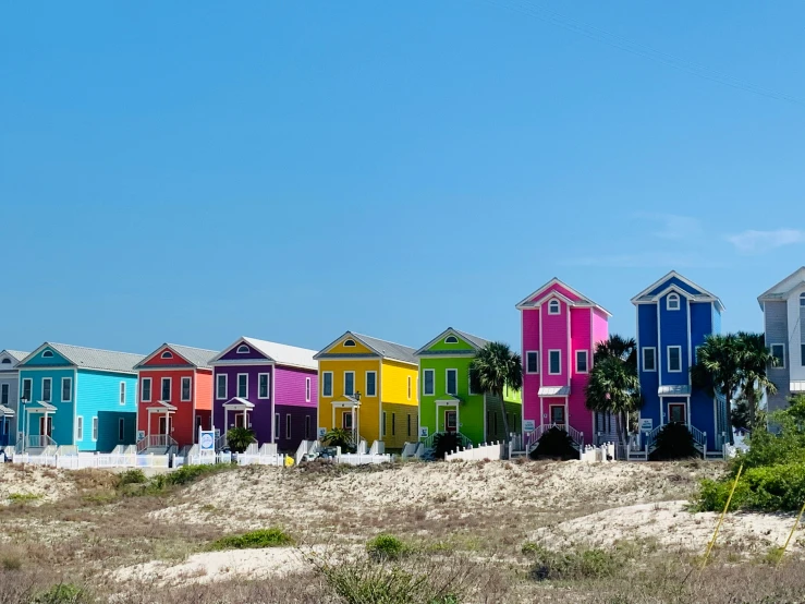 a row of colorful houses sitting on top of a sandy beach, by Carey Morris, pexels contest winner, renaissance, alabama, exterior photo, multiple stories, bright sunny day