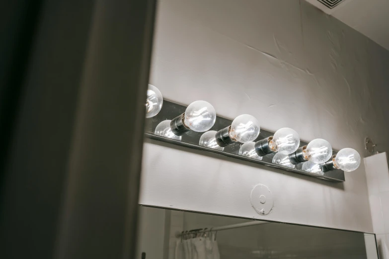 a bathroom light that is on above a mirror, inspired by Elsa Bleda, pexels contest winner, light bulbs, theater dressing room, light inside the hut, minimalist lighting