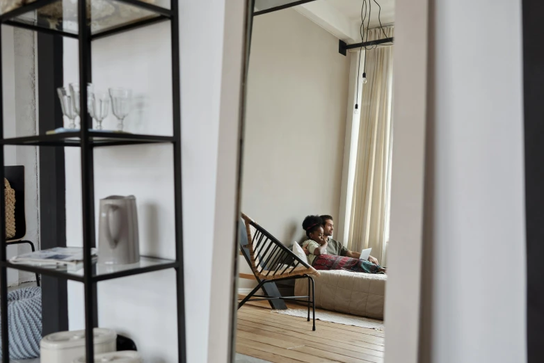 a person sitting on a couch in a living room, by Jan Tengnagel, pexels contest winner, light and space, looking in mirror, interior of a loft, couple on bed, leaning on door