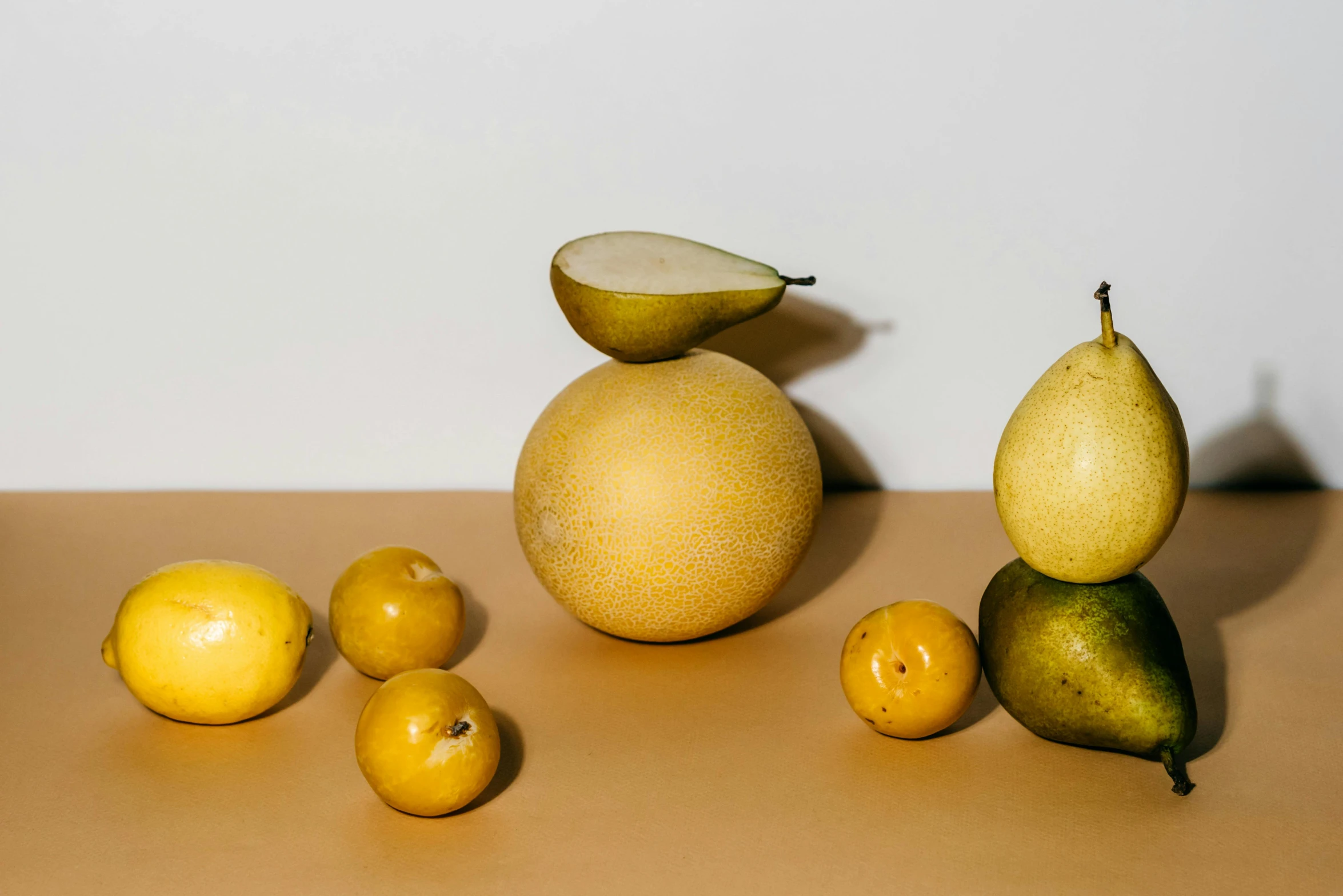 a bunch of fruit sitting on top of a table, by Carey Morris, trending on pexels, muted brown yellow and blacks, pear, spheres, product introduction photo