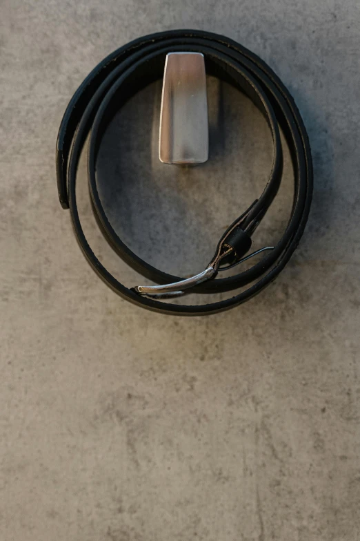 a close up of a cell phone connected to a charger, by Nina Hamnett, leather belt, dark matte metal, concrete, hoses:10