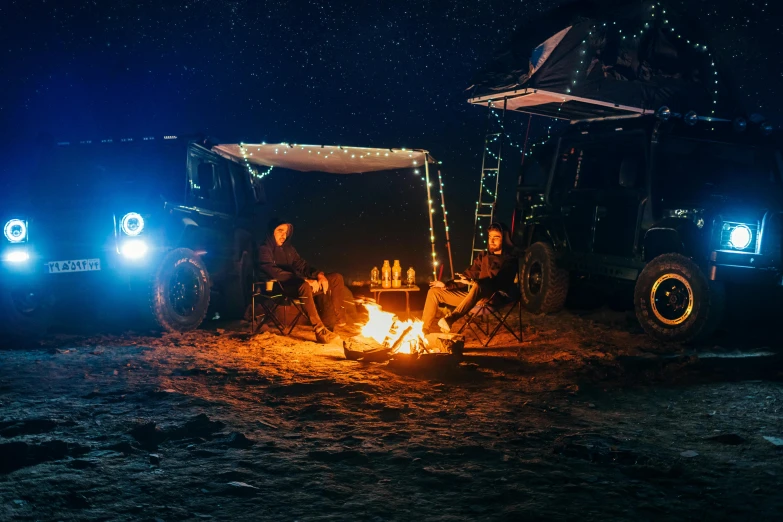 a couple of people sitting around a campfire, hurufiyya, off-roading, fairy lights, profile image, ultrawide cinematic