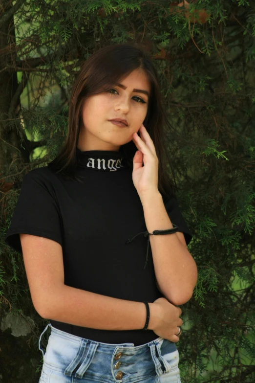 a woman standing in front of a tree talking on a cell phone, by Marie Angel, instagram, wearing intricate black choker, black t shirt, wearing angel, young teen