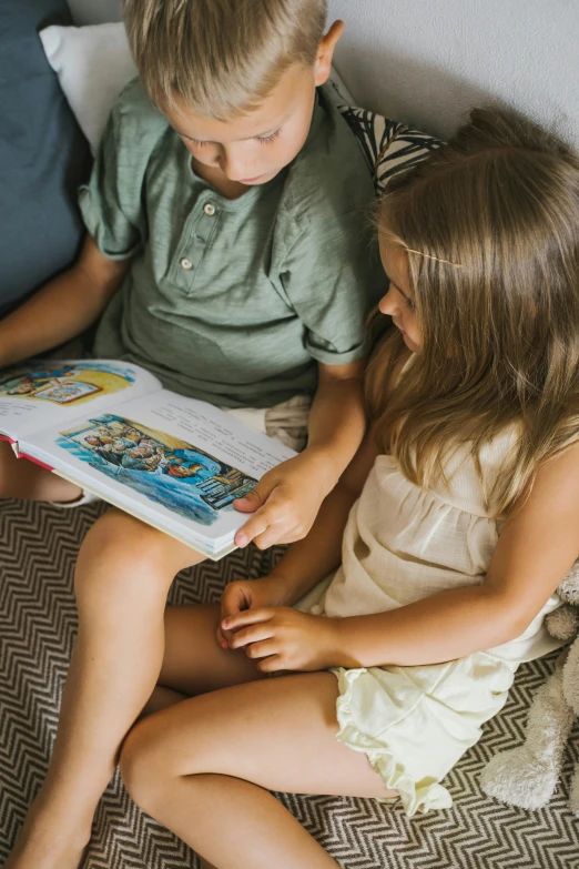 two children sitting on a bed reading a book, zoomed in, te pae, colour corrected, family friendly