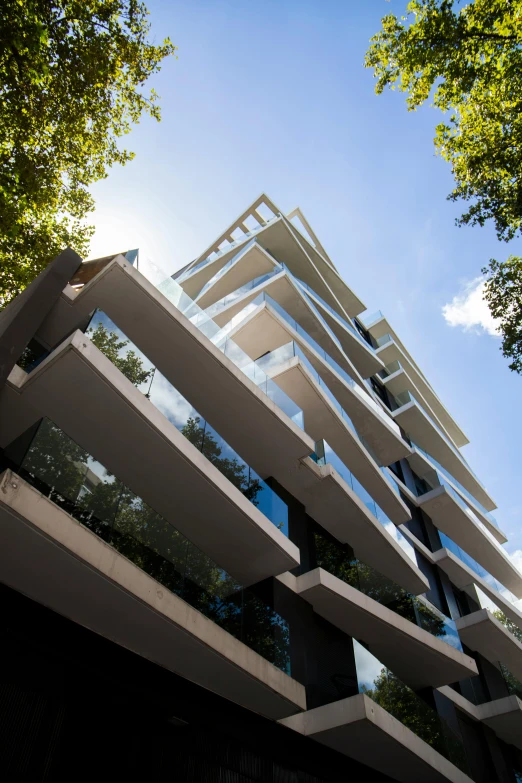 a tall building surrounded by trees on a sunny day, bauhaus, buenos aires, zaha hadid style architecture, front profile, dwell