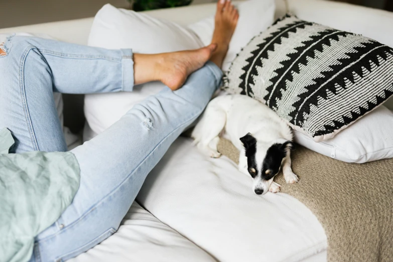 a person laying on a couch with a dog, by Julia Pishtar, denim jeans, white, australian, scandinavian style