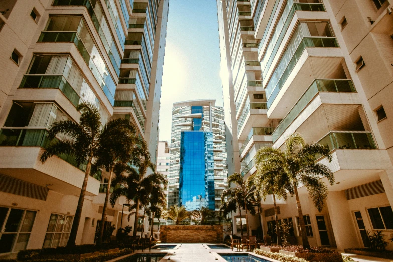 a pool in the middle of a city with tall buildings in the background, by Robbie Trevino, palm trees outside the windows, view from ground level, stacked buildings, high quality upload