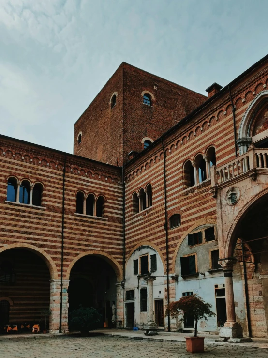 a large brick building with a clock tower, inspired by Gaetano Sabatini, pexels contest winner, inside a castle courtyard, panoramic, venice biennale, profile image