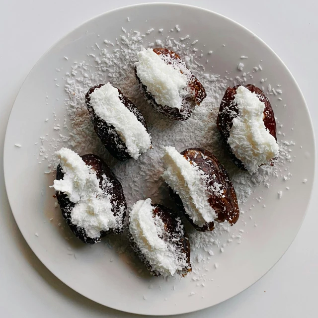 a white plate topped with donuts covered in powdered sugar, inspired by Miyagawa Chōshun, unsplash, hurufiyya, eggplant, black forest, in a row, coconuts