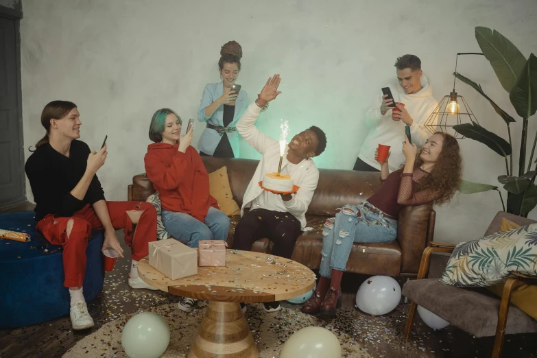 a group of people sitting around a table with a birthday cake, an album cover, trending on pexels, happening, lesbians, background image, sitting in a lounge, video footage