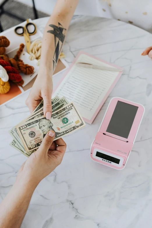 a person handing money to another person at a table, a polaroid photo, by Julia Pishtar, pexels contest winner, pink pastel, holding scale, family photo, instagram story