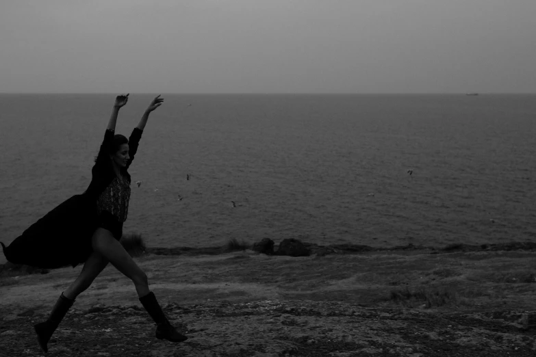 a black and white photo of a woman throwing a frisbee, a black and white photo, unsplash, conceptual art, girl dancing on cliff, anjali mudra, seaview, creepy pose