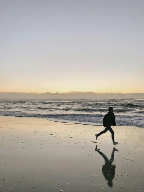 a person walking on a beach near the ocean, on the ocean