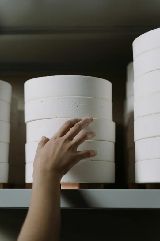 a person reaching for a container on a shelf, inspired by Rachel Whiteread, trending on unsplash, made of swiss cheese wheels, the greatest cake, studio quality product, white sleeves