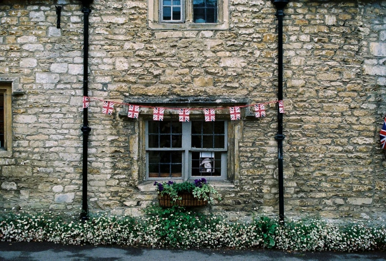 a brick building with a flag hanging from it's side, inspired by Thomas Struth, pexels, folk art, flowery cottage, f 1.4 kodak portra, bath, shopwindows