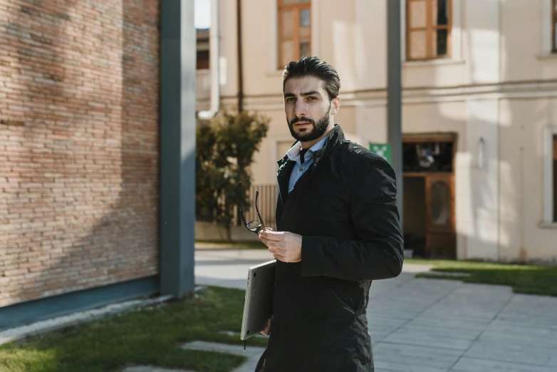 a man in a suit and tie walking down a sidewalk, an album cover, by Alessandro Allori, pexels contest winner, renaissance, holding notebook, ponytail and beard, handsome young man, programmer