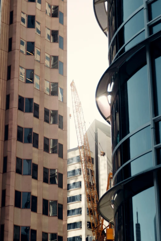 a couple of tall buildings next to each other, a screenshot, by Lee Loughridge, pexels contest winner, sunny light, curvy build, cinematic establishing shot, construction