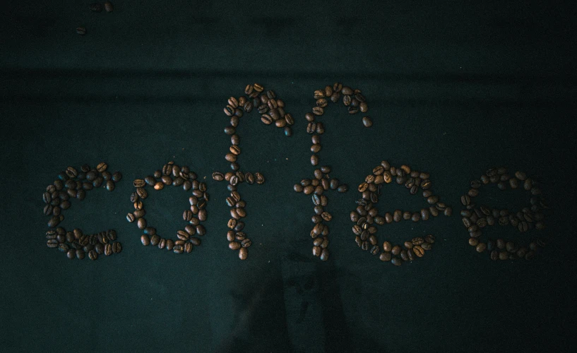 a person standing in front of a wall covered in coffee beans, inspired by Elsa Bleda, pexels contest winner, graffiti, detailed string text, sitting on a mocha-colored table, on black background, # nofilter