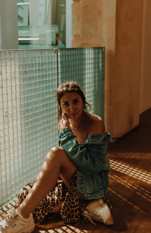 a woman sitting on the ground next to a fence, a picture, inspired by Elsa Bleda, trending on pexels, happening, tanned, indoor picture, backlighted, confident pose