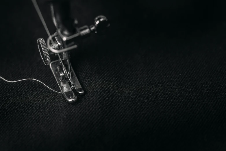 a black and white photo of a sewing machine, trending on pexels, process art, 8k fabric texture details, wearing black clothes, miniature product photo, black flat background