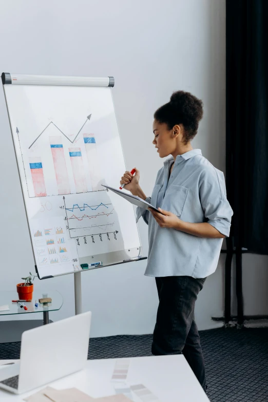 a woman standing in front of a whiteboard in an office, analytical art, giving a speech, graphs, 2019 trending photo, african american woman