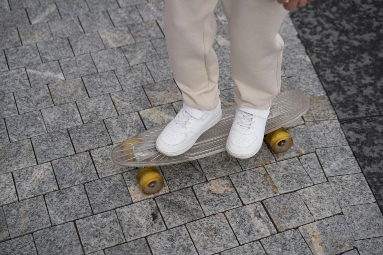a person standing on a skateboard on a sidewalk, white and silver, on top of it, on a white table