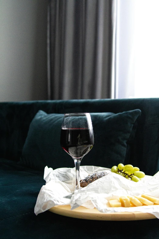 a tray of food and a glass of wine on a couch, black+velvet+red+turquoise, linen, city morning, grapes