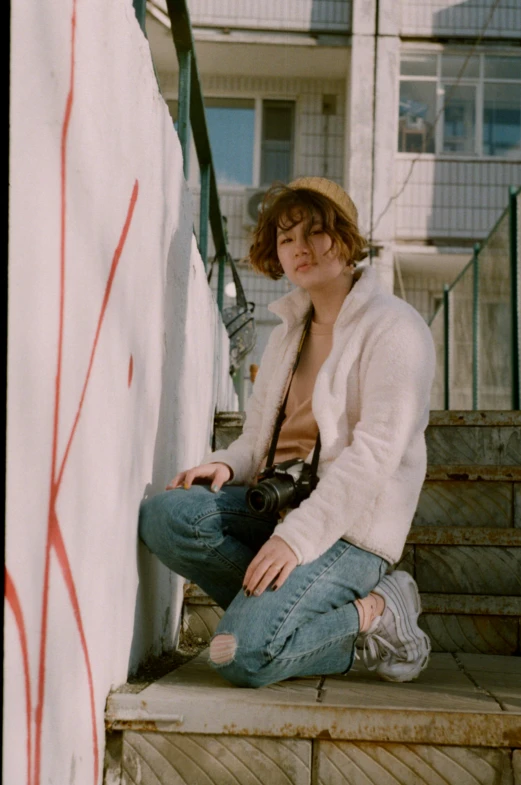 a young man sitting on the steps of a building, an album cover, inspired by Elsa Bleda, trending on pexels, graffiti, portrait androgynous girl, 35mm film still from 1989, brown haired, joey king