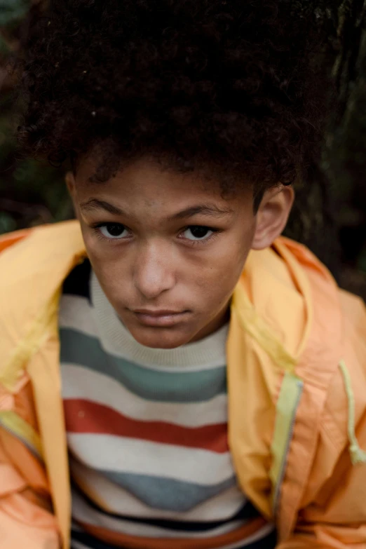 a young boy sitting on the ground next to a fire hydrant, an album cover, unsplash, visual art, model wears a puffer jacket, yellow - orange eyes, 14 yo berber boy, stripes