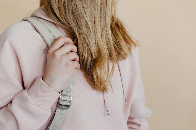 a close up of a person with a backpack, by Alice Mason, trending on pexels, happening, wearing a pastel pink hoodie, sustainable materials, arm around her neck, leather straps