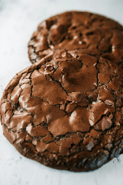 a close up of two chocolate cookies on a table, by Jessie Algie, glowing cracks, side profile view, rugged face, rich details full of texture
