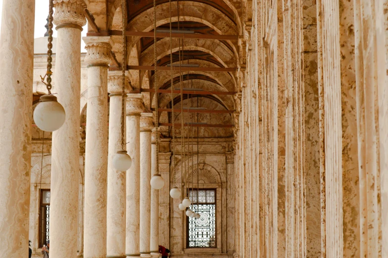 a person sitting on a bench in a building, by Canaletto, pexels contest winner, neoclassicism, archways between stalagtites, islamic, tall columns, profile image