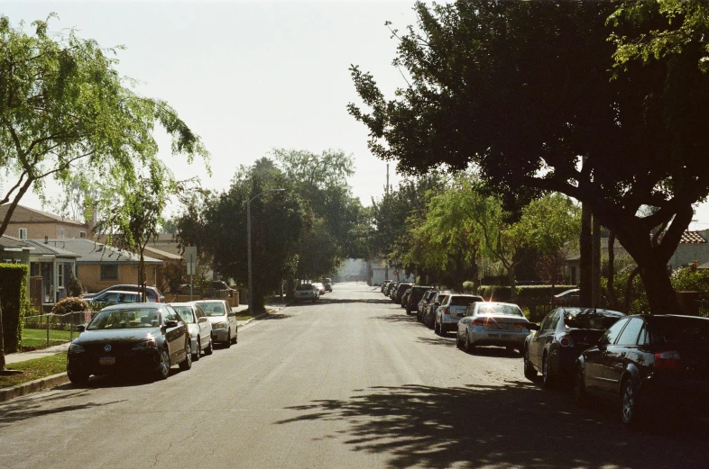 a street filled with lots of parked cars, by Ryan Pancoast, 1990s photograph, trees outside, los angeles 2 0 1 5, summer afternoon