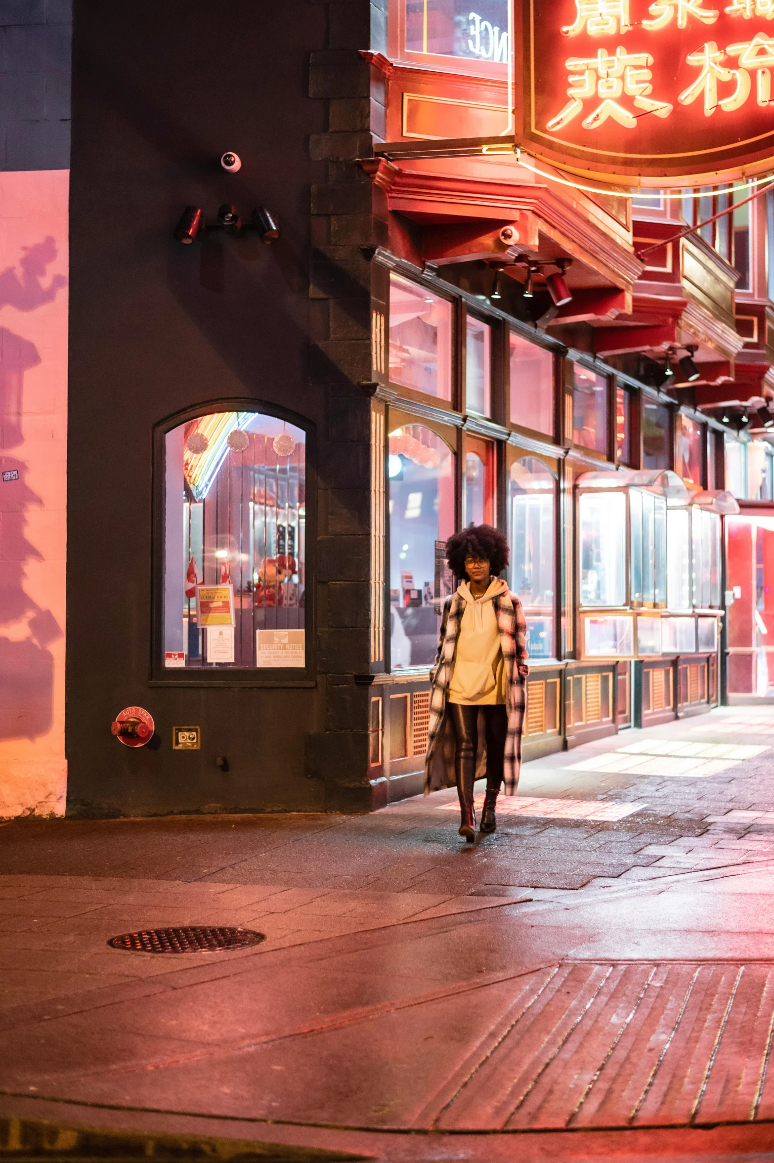 a woman walking down a city street at night, by Emanuel Witz, trending on unsplash, graffiti, reddish exterior lighting, imaan hammam, exiting store, outside a saloon