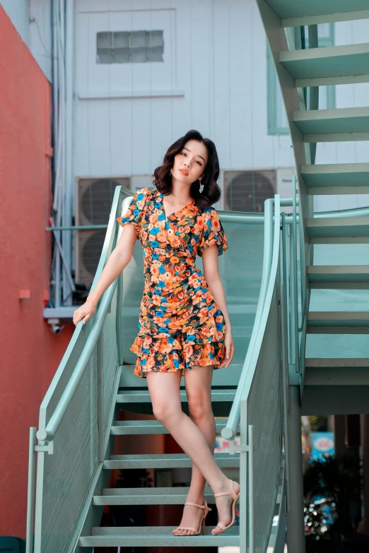 a woman standing on a set of stairs, a portrait, by Robbie Trevino, unsplash, lady with glowing flowers dress, korean women's fashion model, orange and teal, square