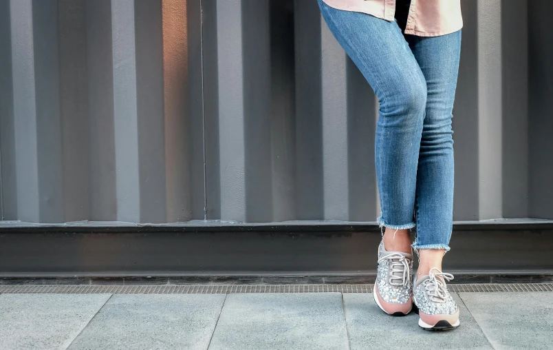 a woman standing on a sidewalk holding a cell phone, trending on pexels, graffiti, blue jeans and grey sneakers, glitter gif, background image, standing in a restaurant