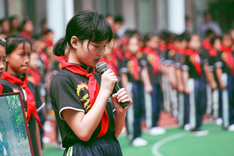 a woman holding a microphone in front of a crowd, by Bernardino Mei, pexels contest winner, school uniform, beijing, girl wearing uniform, contemplating