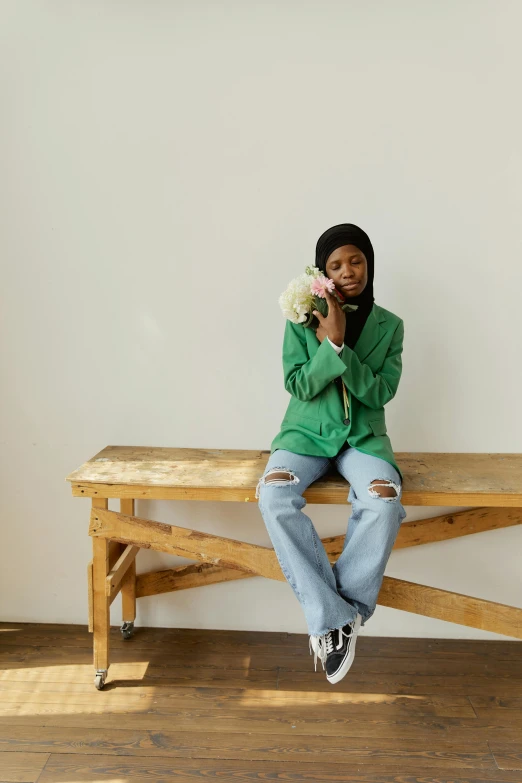 a man sitting on top of a wooden bench, an album cover, by Dulah Marie Evans, wearing green jacket, hijab, holding a rose, baggy jeans