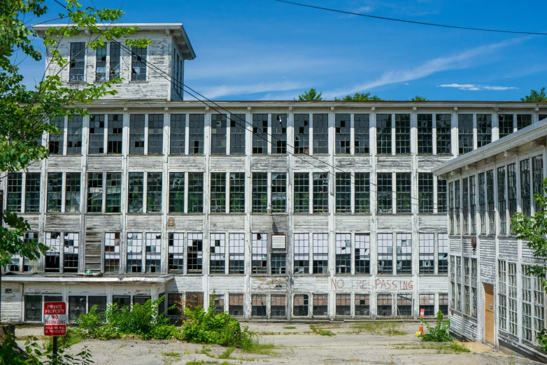 an old building with lots of windows and a clock tower, inspired by Robert Bechtle, pexels contest winner, old lumber mill remains, new hampshire, panoramic, concrete building