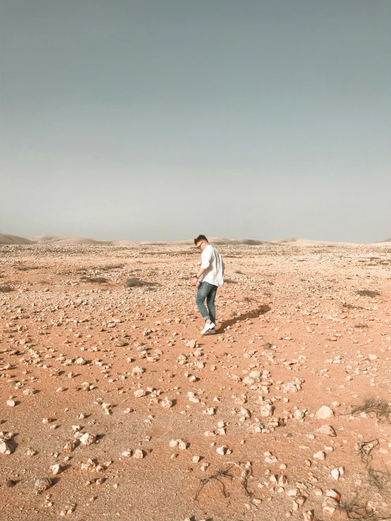 a man is flying a kite in the desert, an album cover, by Ismail Acar, pexels contest winner, happening, walking boy, 🤠 using a 🖥, panoramic photography, imbalanced mars. rugged