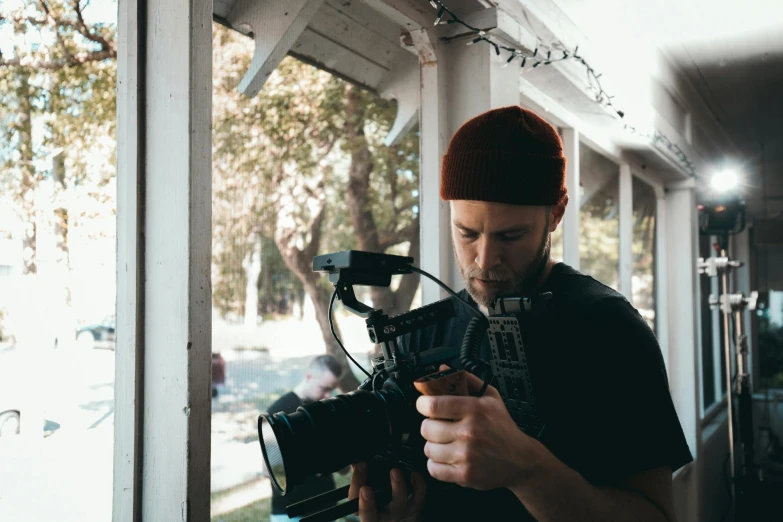 a man holding a camera in front of a window, facing the camera