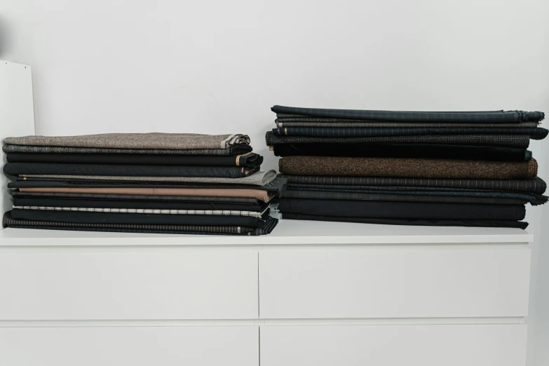 a stack of clothes sitting on top of a dresser, private press, dark grey, fabrics, brown, innovation