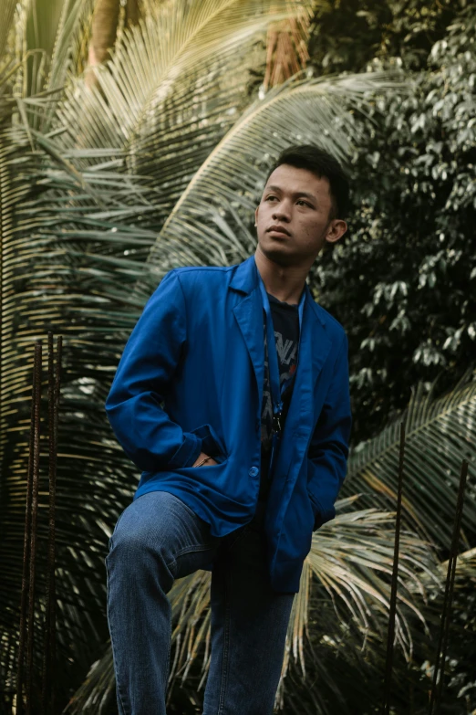 a man in a blue jacket posing for a picture, an album cover, pexels contest winner, sumatraism, greenery, ruan jia and brom, overcast, looking left