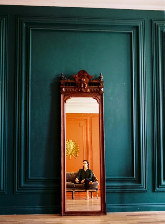 a person sitting on a couch in front of a mirror, inspired by Elsa Bleda, baroque, copper and deep teal mood, architectural digest photo, smooth panelling, profile image