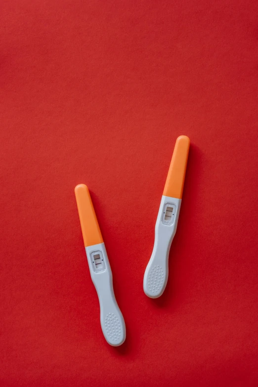 two toothbrushes sitting next to each other on a red surface, by Romain brook, white and orange, pregnancy, fan favorite, led indicator