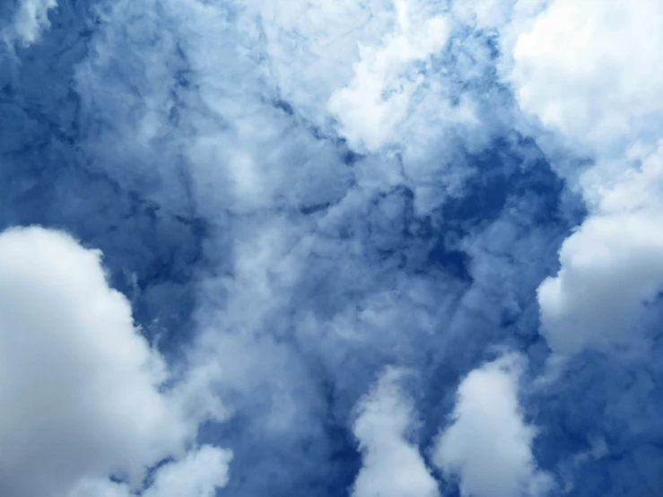 a plane flying through a cloudy blue sky, an album cover, by Carey Morris, unsplash, surrealism, cumulus clouds, high definition photo, nebula clouds, a close-up