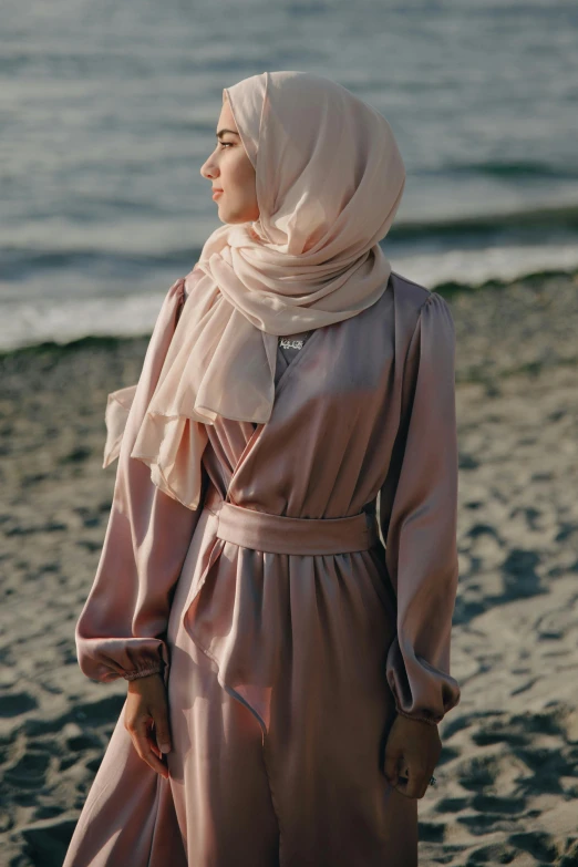 a woman standing on top of a sandy beach, inspired by Maryam Hashemi, trending on pexels, hurufiyya, soft silk dress, light blush, scarf, malaysian